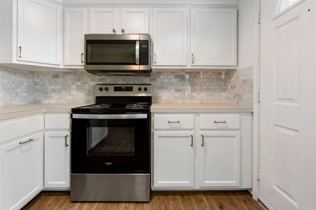 a kitchen with granite countertop white cabinets and stainless steel appliances