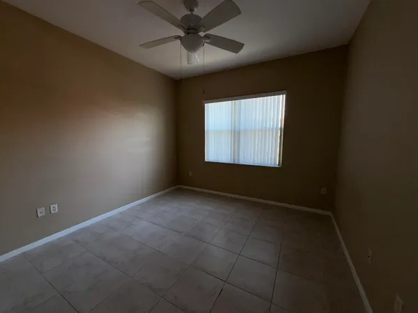 an empty room with a window and a fan
