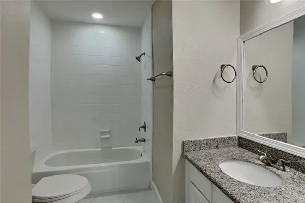 a bathroom with a granite countertop sink a toilet and shower