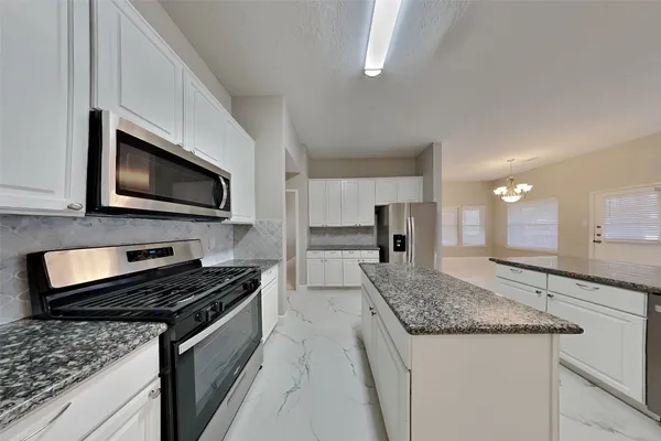 a kitchen with granite countertop a sink and a stove top oven