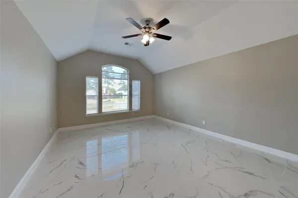an empty room with chandelier fan and windows