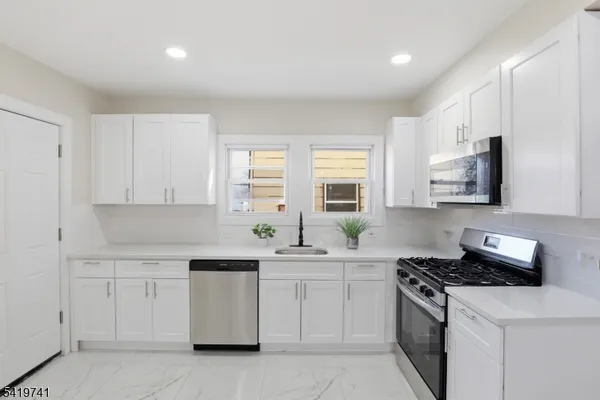 a kitchen with white cabinets and appliances