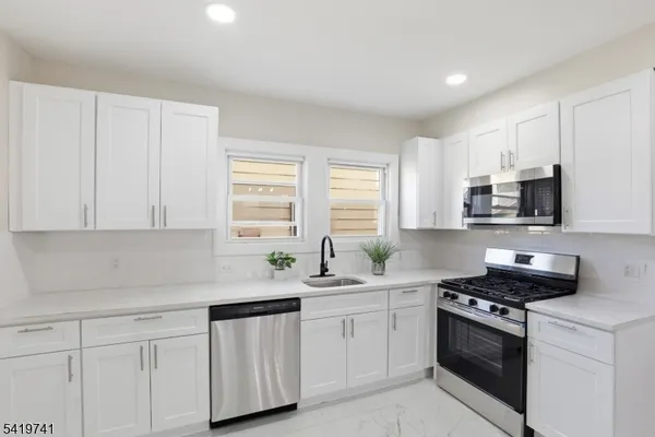 a kitchen with stainless steel appliances white cabinets and a sink