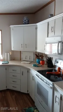 a kitchen with granite countertop white cabinets and white appliances