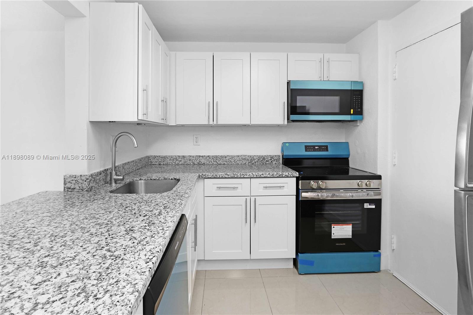 9001 Southwest 77th Avenue, Unit C803 Miami, FL 33156 - Photo 14 of 20 a kitchen with stainless steel appliances granite countertop a stove microwave and sink