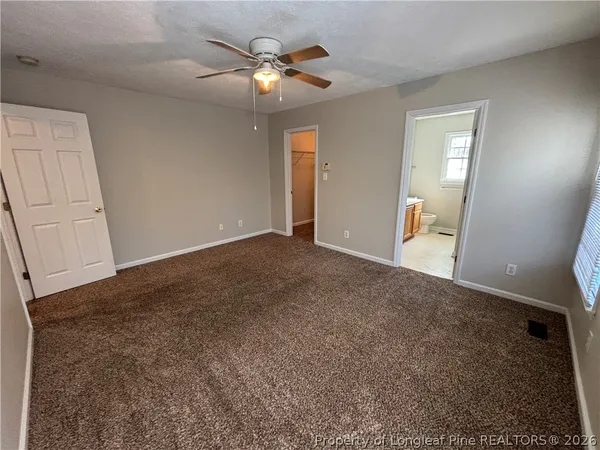 an empty room with chandelier fan and windows