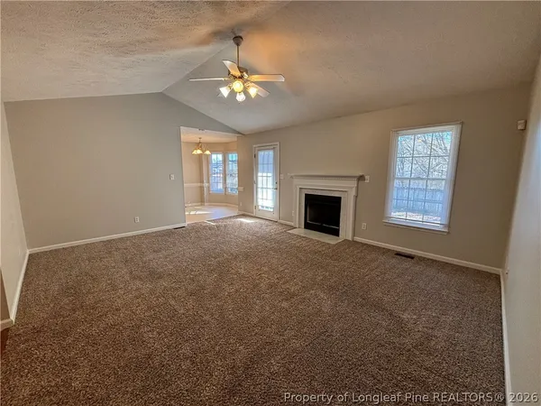 a view of an empty room with chandelier and fireplace
