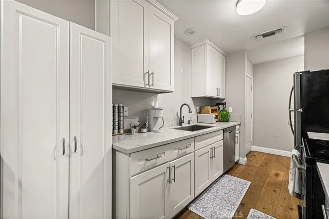 a kitchen with stainless steel appliances granite countertop a refrigerator sink and white cabinets