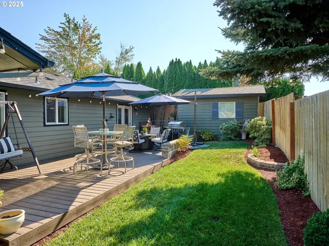 a view of a patio with table and chairs under an umbrella with wooden fence