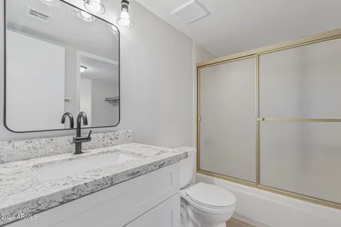 a bathroom with a granite countertop sink toilet and shower