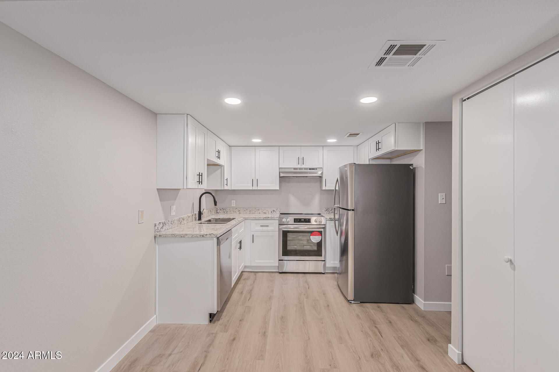 7930 East Camelback Road, Unit 506 Scottsdale, AZ 85251 - Photo 10 of 58 a kitchen with stainless steel appliances granite countertop a refrigerator a sink dishwasher a stove and white countertops with wooden floor