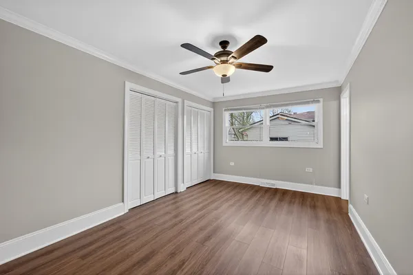 a view of empty room with wooden floor and fan