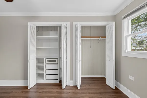 a view of an empty room with wooden floor and closet