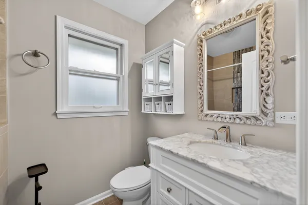 a bathroom with a granite countertop sink a toilet and a mirror