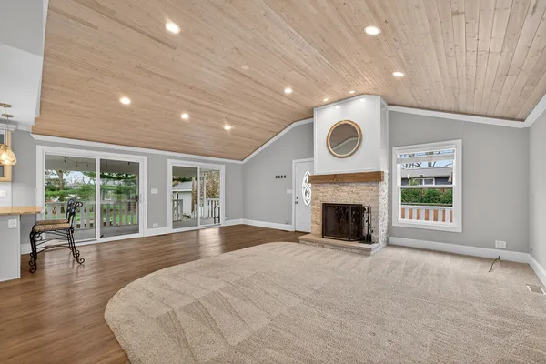 a view of an empty room with wooden floor and a fireplace