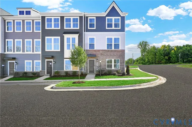 a front view of a residential apartment building with a yard and trees