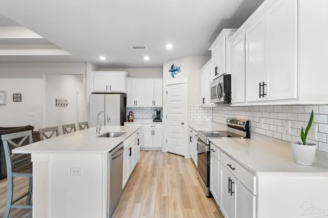 a kitchen with white cabinets sink and stove