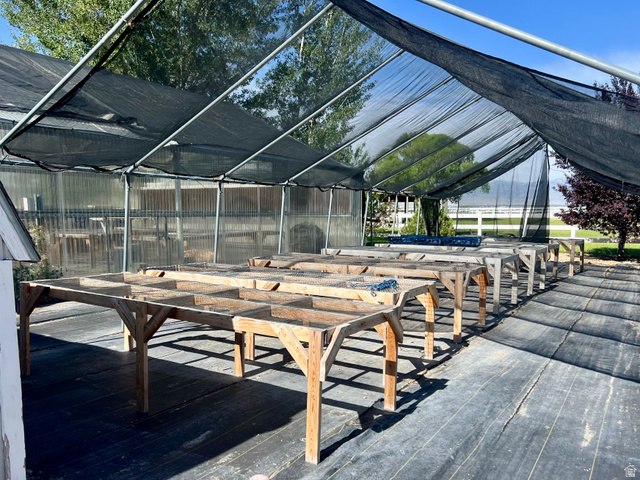 812 East Bates Cyn Road Tooele, UT 84074 - Photo 111 of 144 Greenhouse structure featuring a black shade cloth roof, transparent side panels, and multiple wooden plant benches