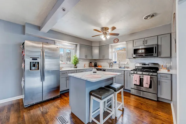 a kitchen with kitchen island a counter top space a stainless steel appliances and cabinets