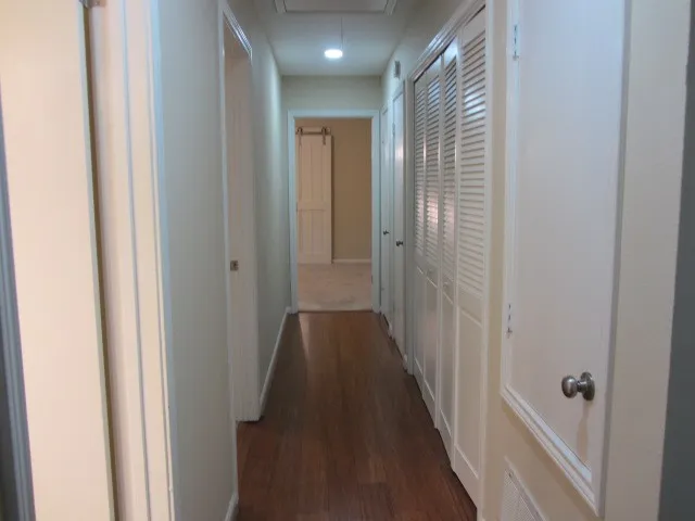 a view of a hallway with wooden floor and a bathroom