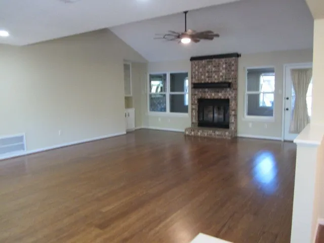 an empty room with wooden floor fireplace and a window
