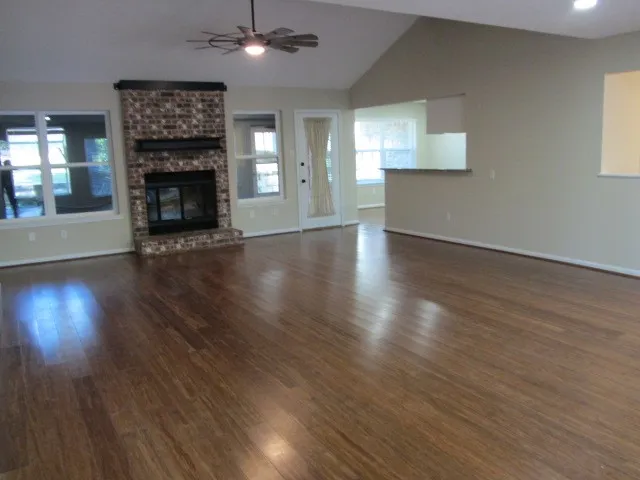 an empty room with wooden floor fireplace and windows