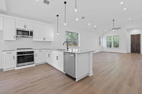a kitchen with stainless steel appliances granite countertop a stove a sink and a microwave