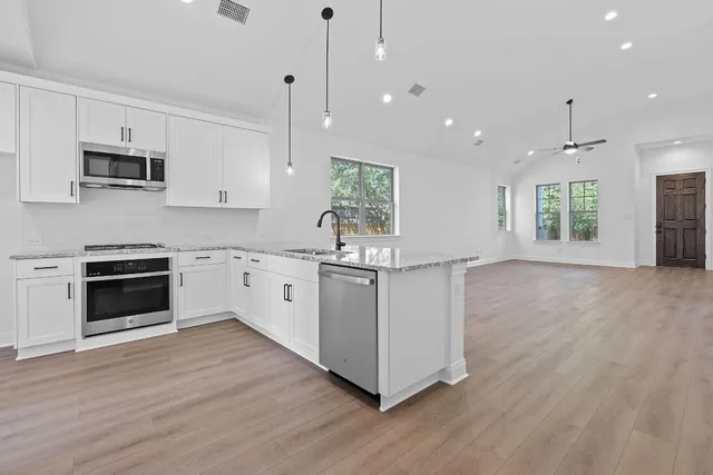 a kitchen with stainless steel appliances granite countertop a stove a sink and a microwave