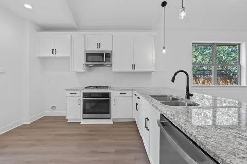 a kitchen with granite countertop a sink and a stove top oven