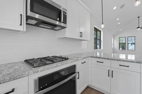 a kitchen with stainless steel appliances granite countertop a sink stove and microwave