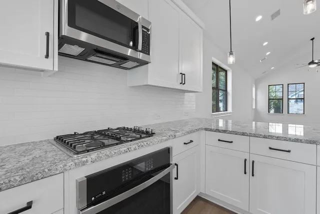 a kitchen with stainless steel appliances granite countertop a sink stove and microwave
