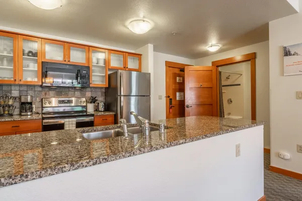 a kitchen with stainless steel appliances granite countertop a refrigerator a stove and a sink with wooden floor