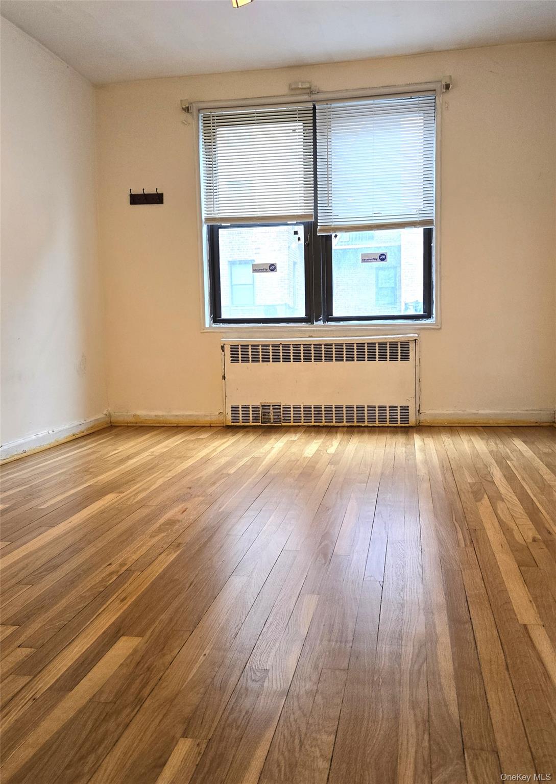 150-11 72nd Road, Unit 1C Queens, NY 11367 - Photo 11 of 25 Spare room featuring radiator heating unit and light wood-style floors