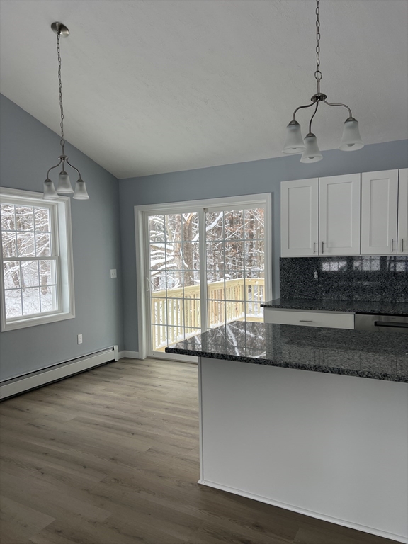 248 Holtshire Road, Unit LOT 2 Orange, MA 01364 - Photo 4 of 12 a large kitchen with granite countertop a stove a sink and white cabinets with wooden floor