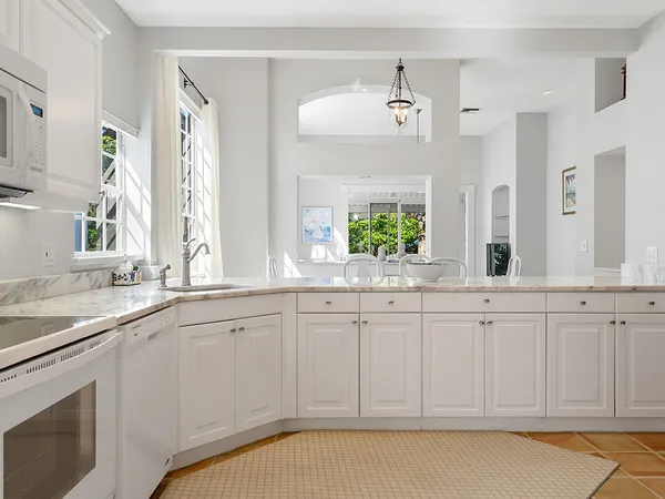 a kitchen with kitchen island granite countertop white cabinets and window
