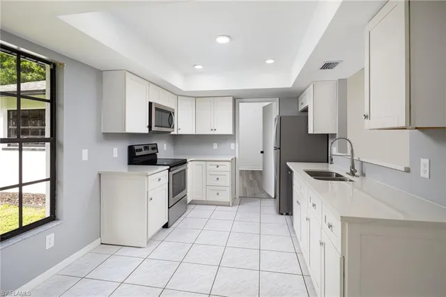 a kitchen with white cabinets a sink stove and refrigerator