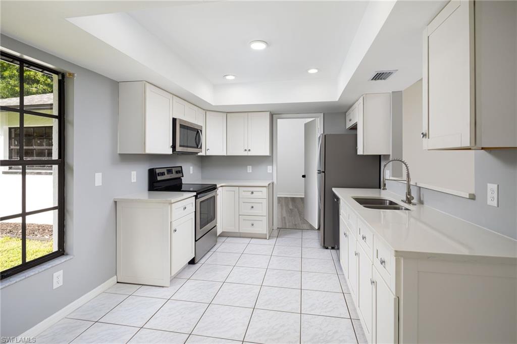 5671 Green Boulevard Naples, FL 34116 - Photo 15 of 37 a kitchen with white cabinets a sink stove and refrigerator