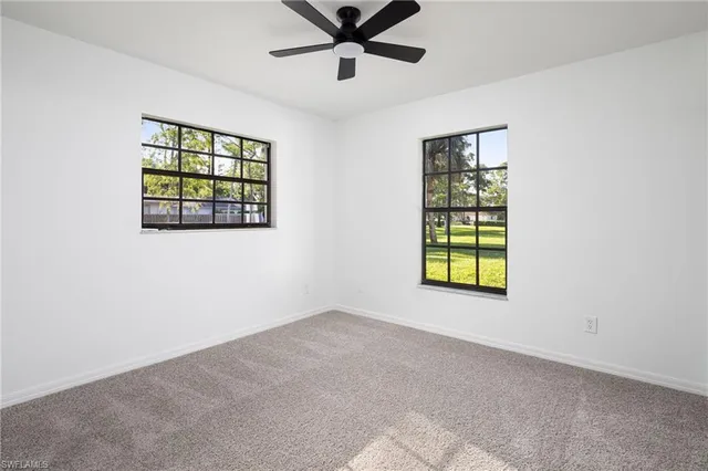 an empty room with windows and ceiling fan