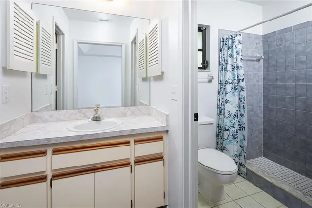 a bathroom with a granite countertop sink a toilet a shower and a mirror
