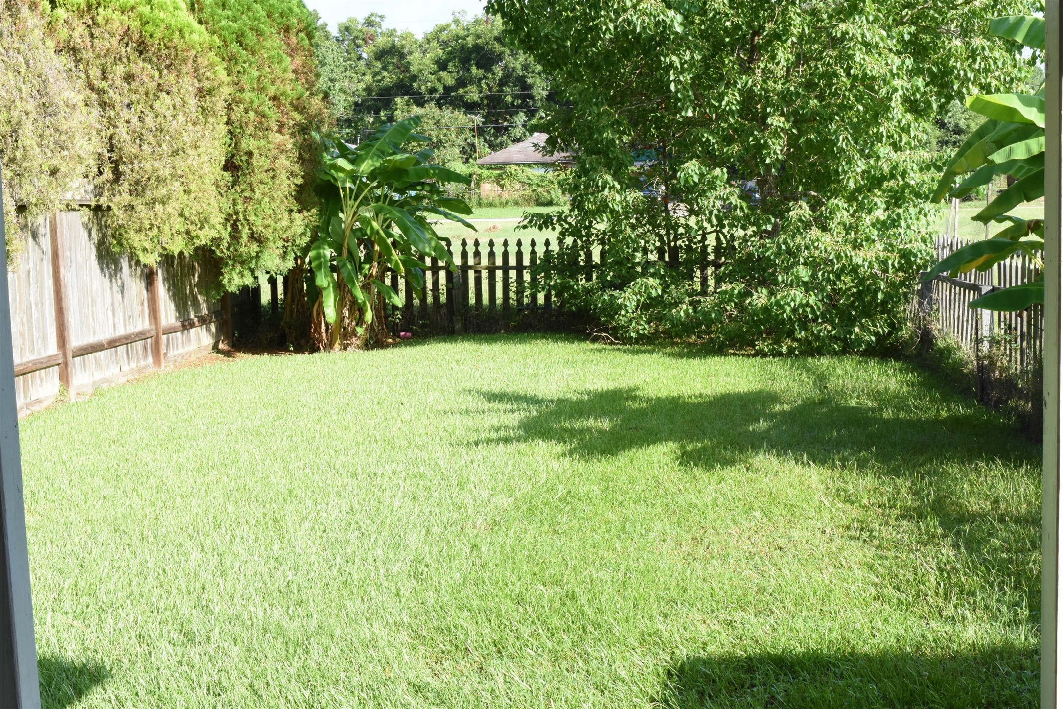 518 Moore Street Tomball, TX 77375 - Photo 18 of 18 This unit features a fenced backyard with trees and lush grass for outdoor play.