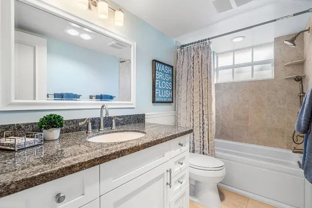a bathroom with a granite countertop sink mirror vanity and toilet