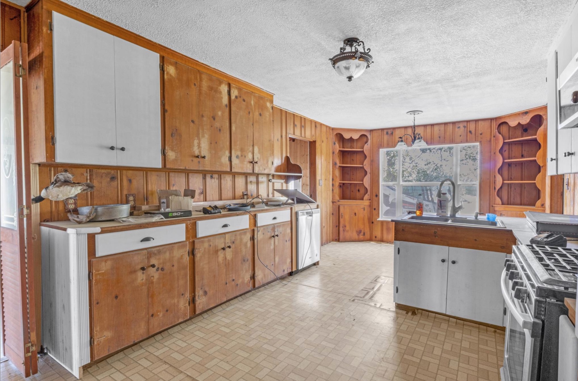 451 Pleasant Grove Road Elgin, TX 78621 - Photo 5 of 26 Kitchen featuring wooden walls, a textured ceiling, stainless steel appliances, and a sink