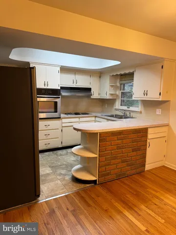 a kitchen with kitchen island granite countertop a sink cabinets and stainless steel appliances