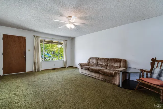 an empty room with a chandelier fan and windows