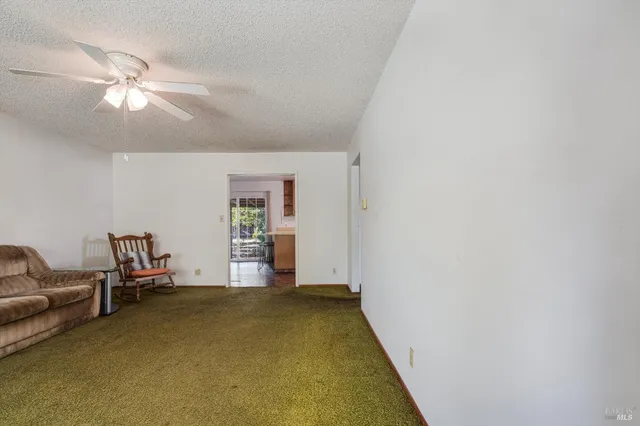 an empty room with chandelier fan and windows