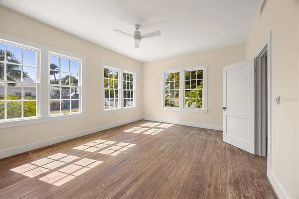 a view of an empty room with a window and wooden floor
