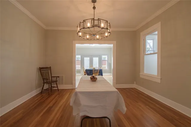 a dining room with wooden floor a chandelier a wooden table and chairs