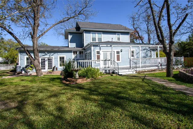 a view of a house with a yard deck and a large tree