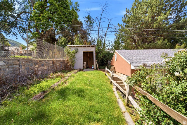 1341 29th Street Ogden, UT 84403 - Photo 29 of 37 Expansive outdoor space featuring a manicured lawn, a detached storage shed, a stone retaining wall, and mature perimeter trees