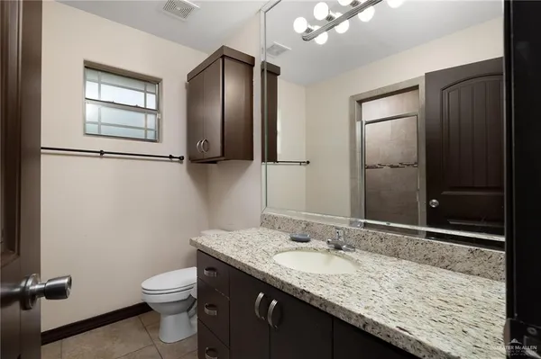 a bathroom with a granite countertop sink toilet and mirror